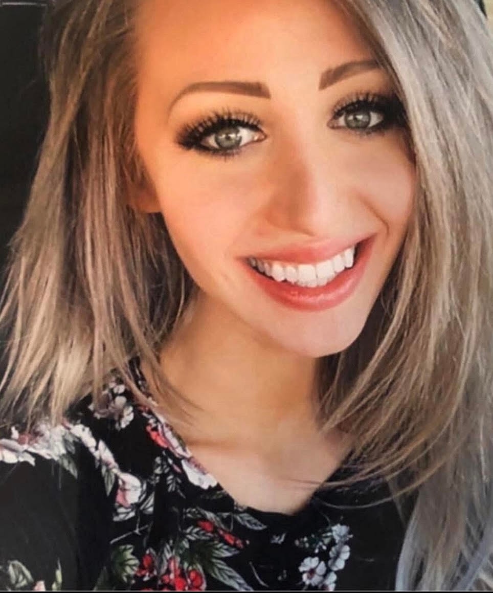 Smiling woman with long hair and floral shirt.