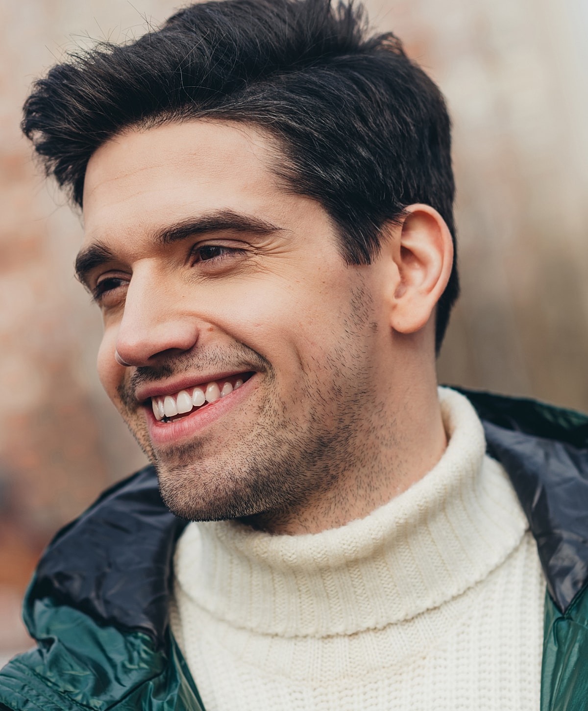 Smiling man in a cozy sweater outdoors.