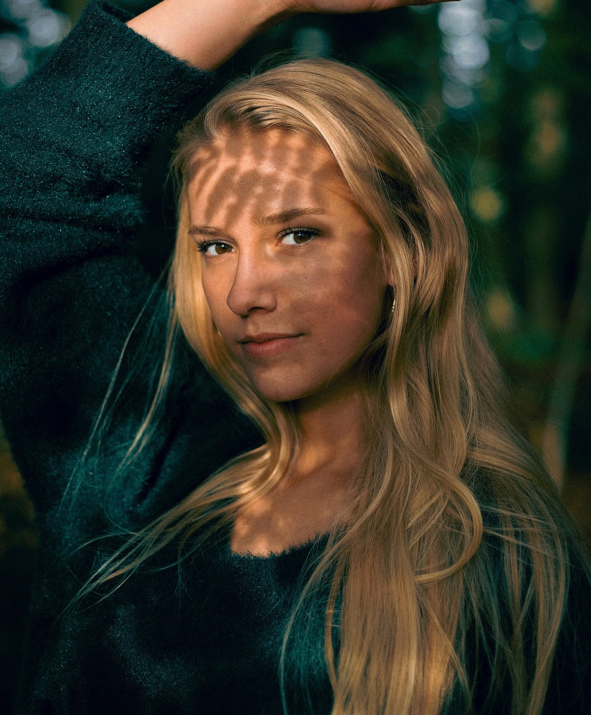Person with long hair in dappled sunlight.