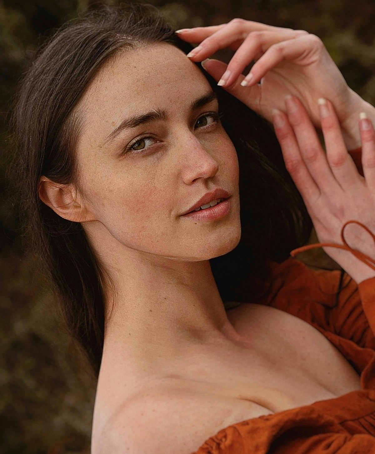 Woman with long hair in rust-colored top.