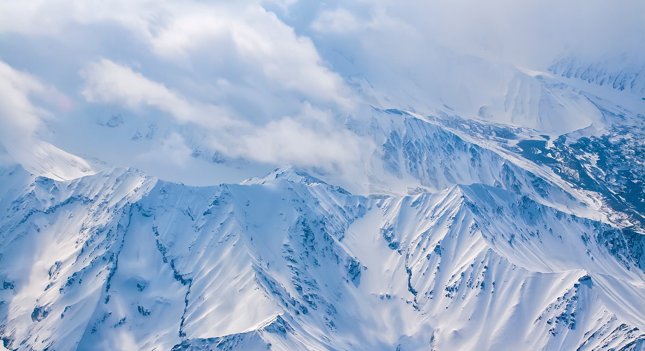 Snow-covered mountain peaks under cloudy sky.