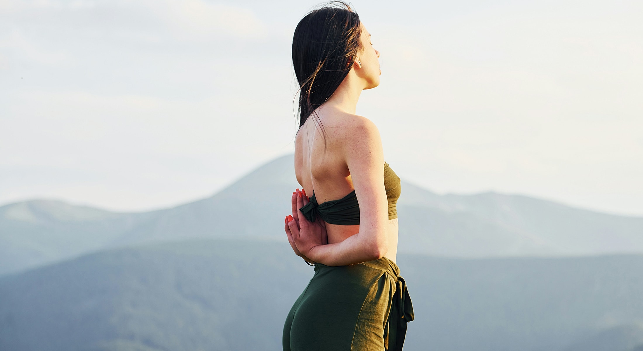 Wasilla Sun Damage Treatment model practicing yoga in nature with mountains.