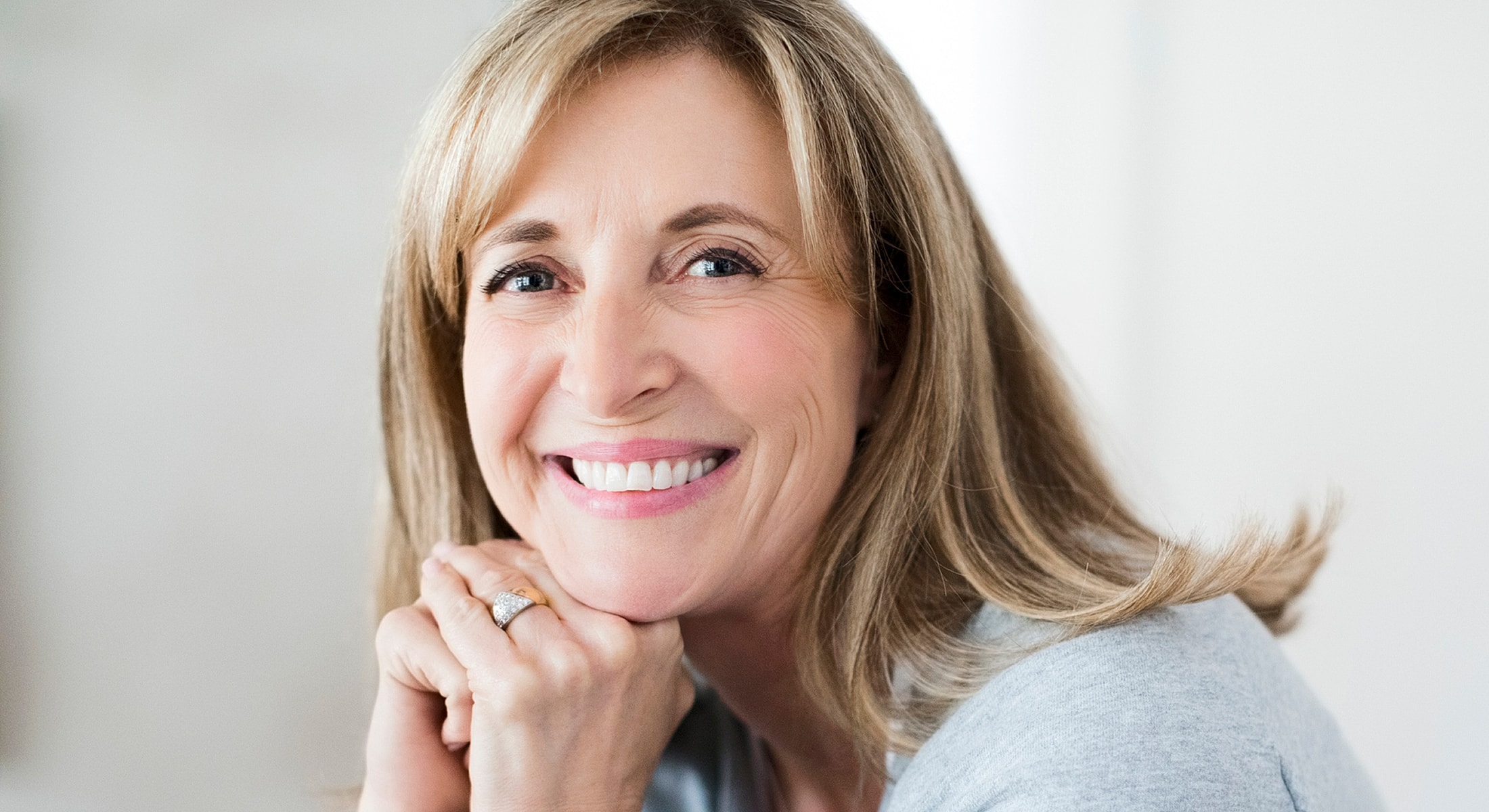 Smiling woman resting chin on hands.
