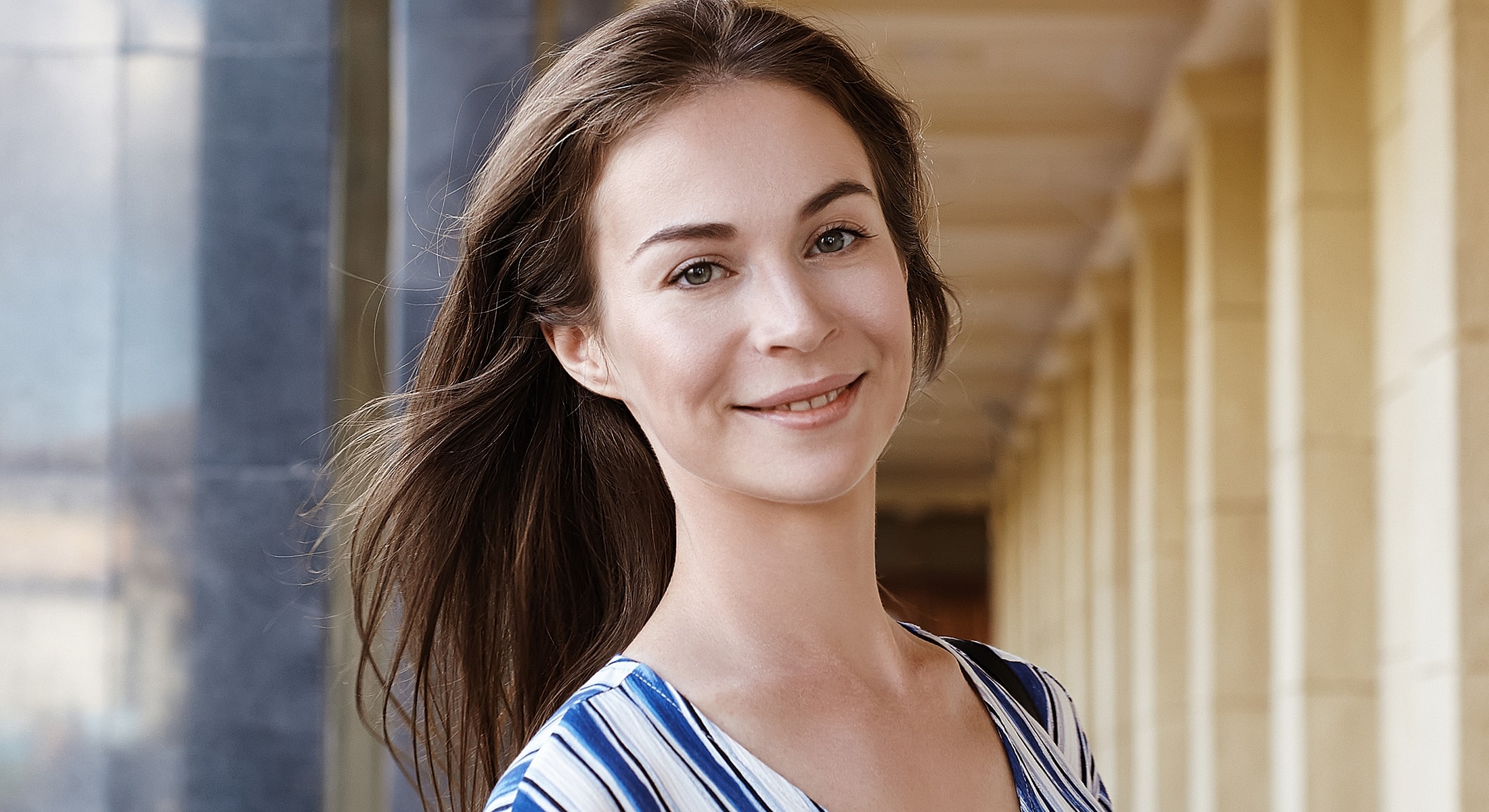 Smiling woman in a striped dress outdoors.