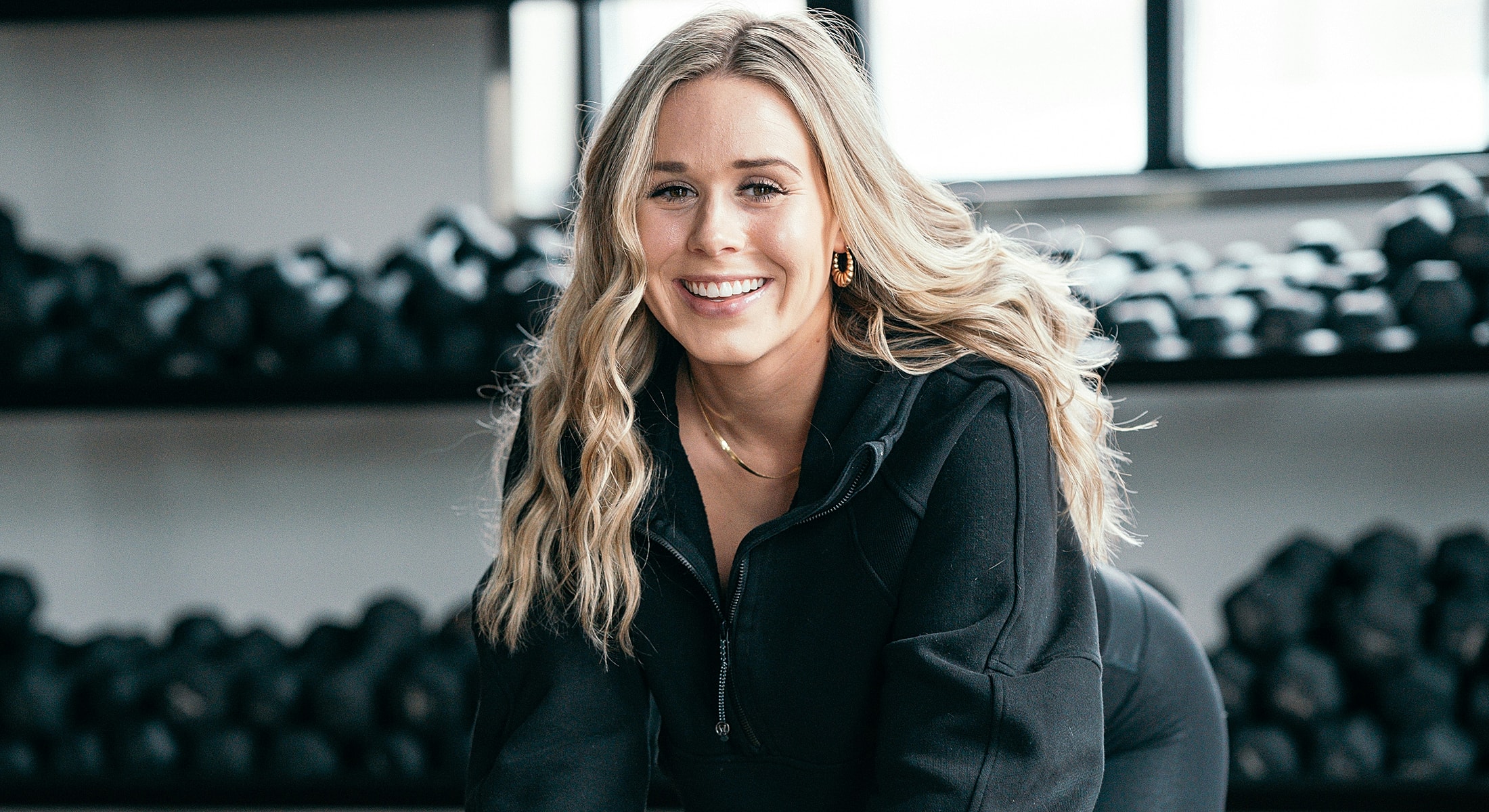 Smiling woman in gym wearing athletic clothing.