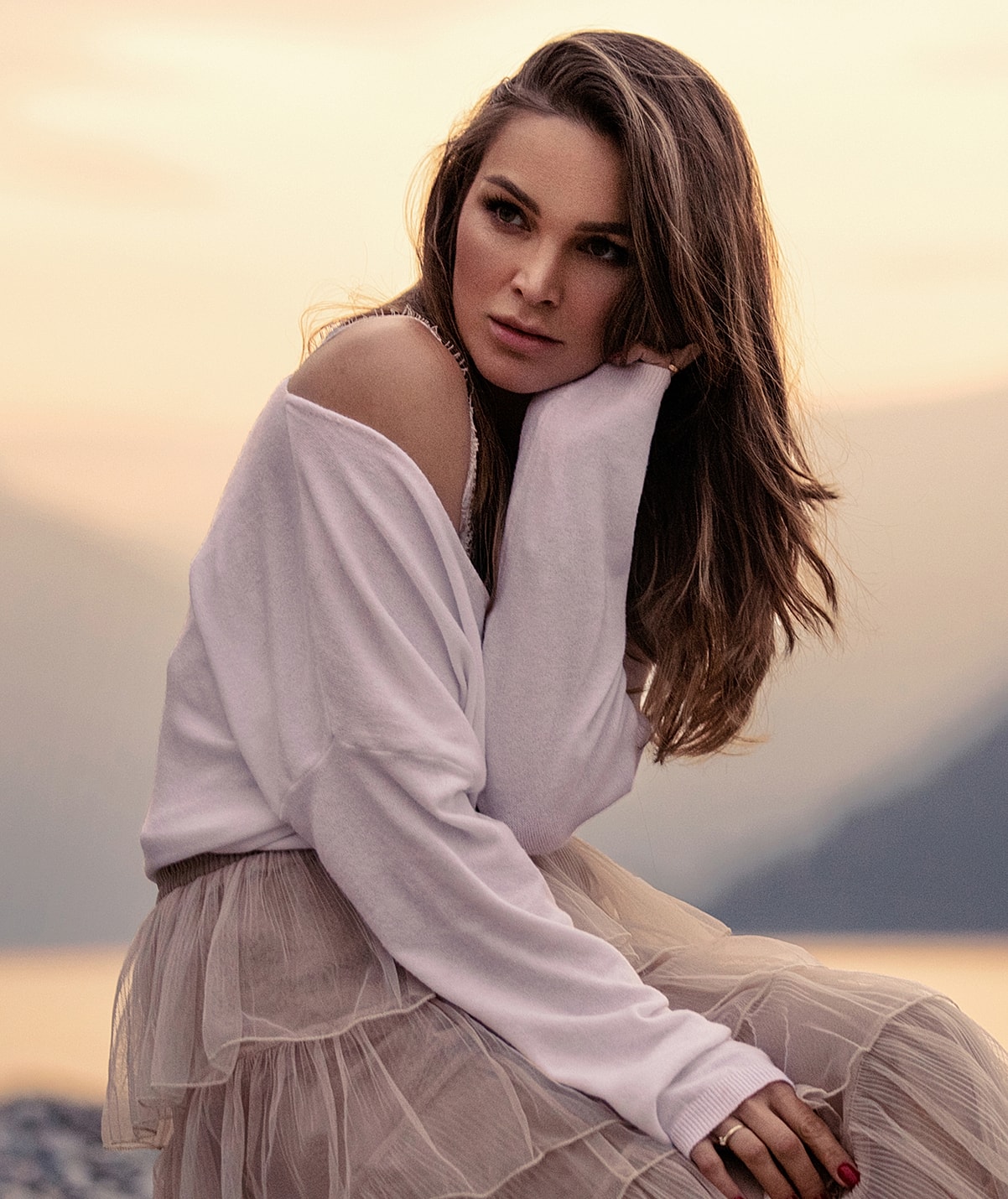 Woman in soft attire, posing by the water.