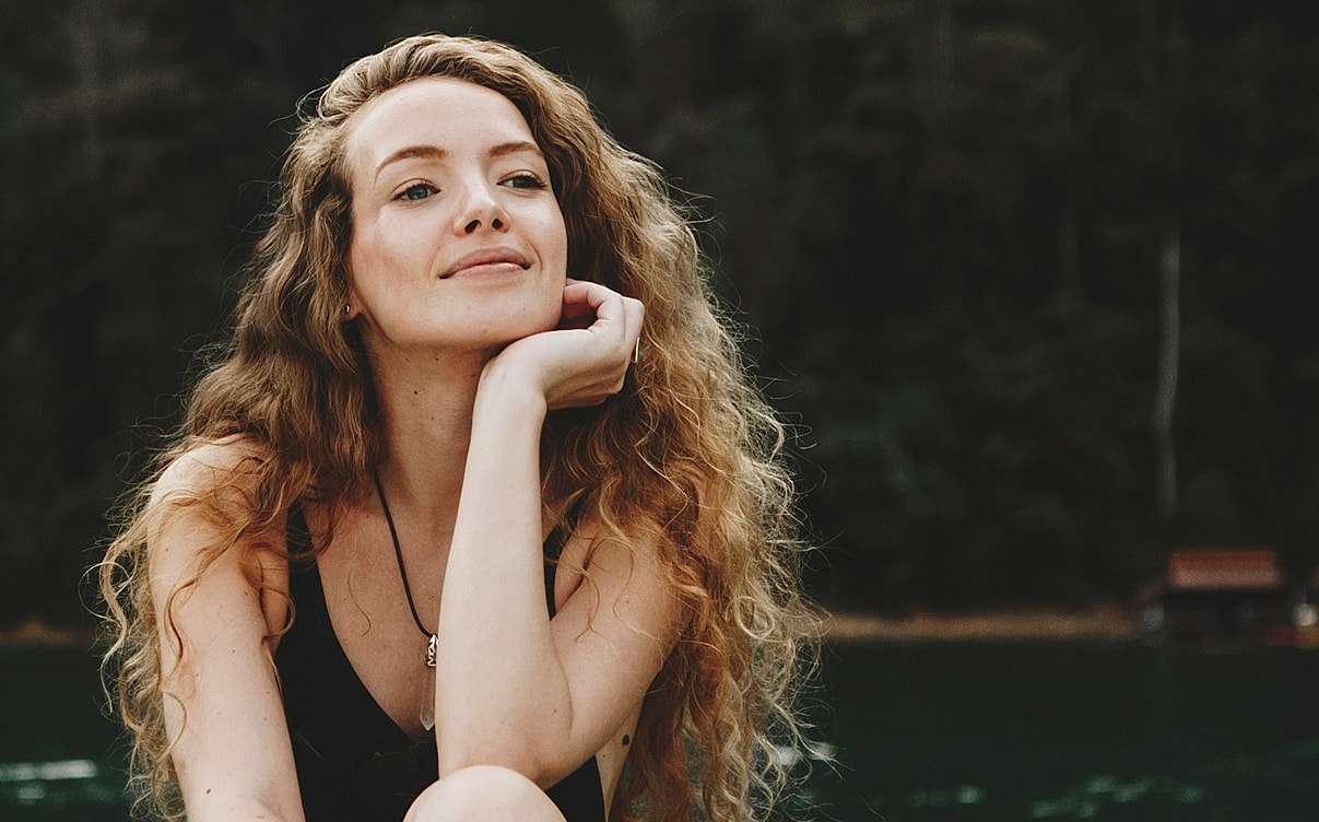 Woman with curly hair against a natural background.
