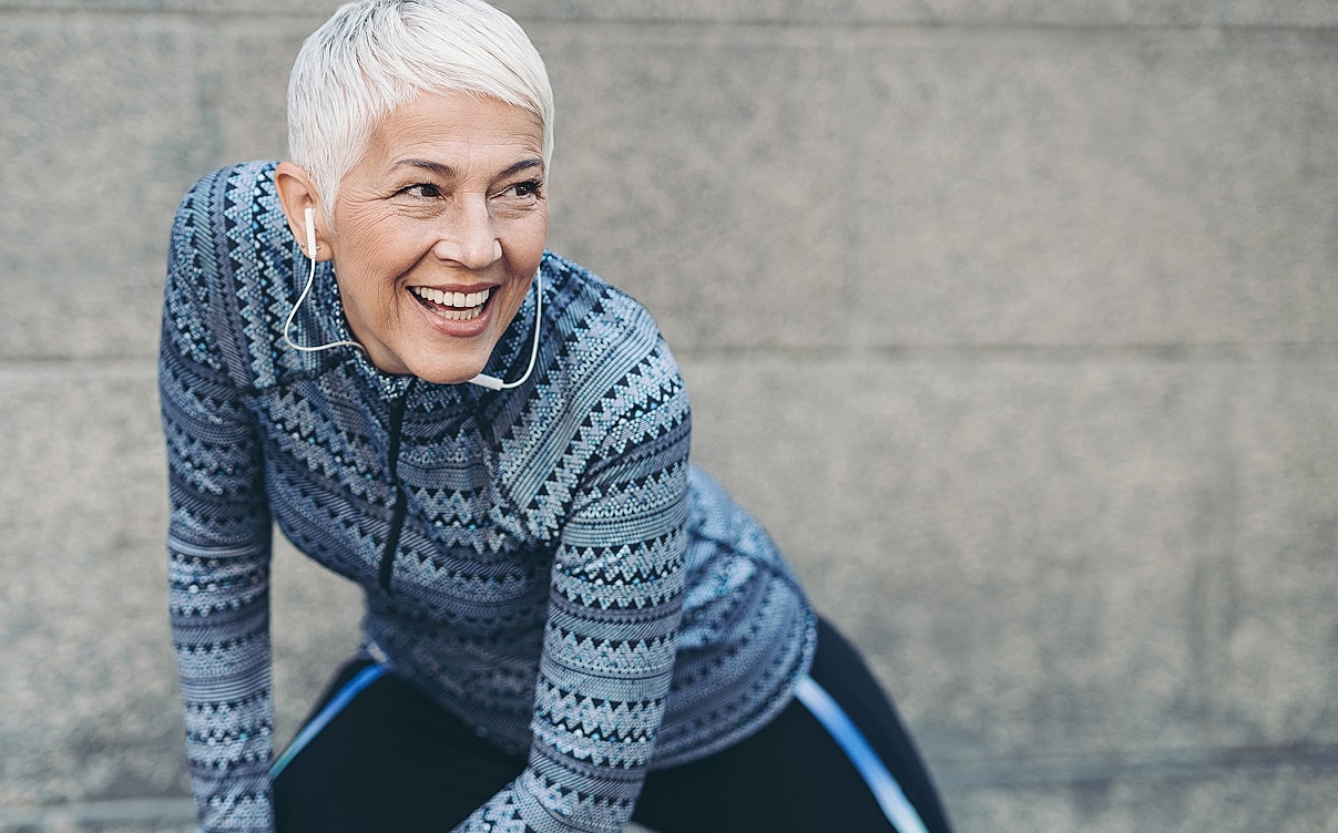 Smiling woman in athletic wear listening to music.