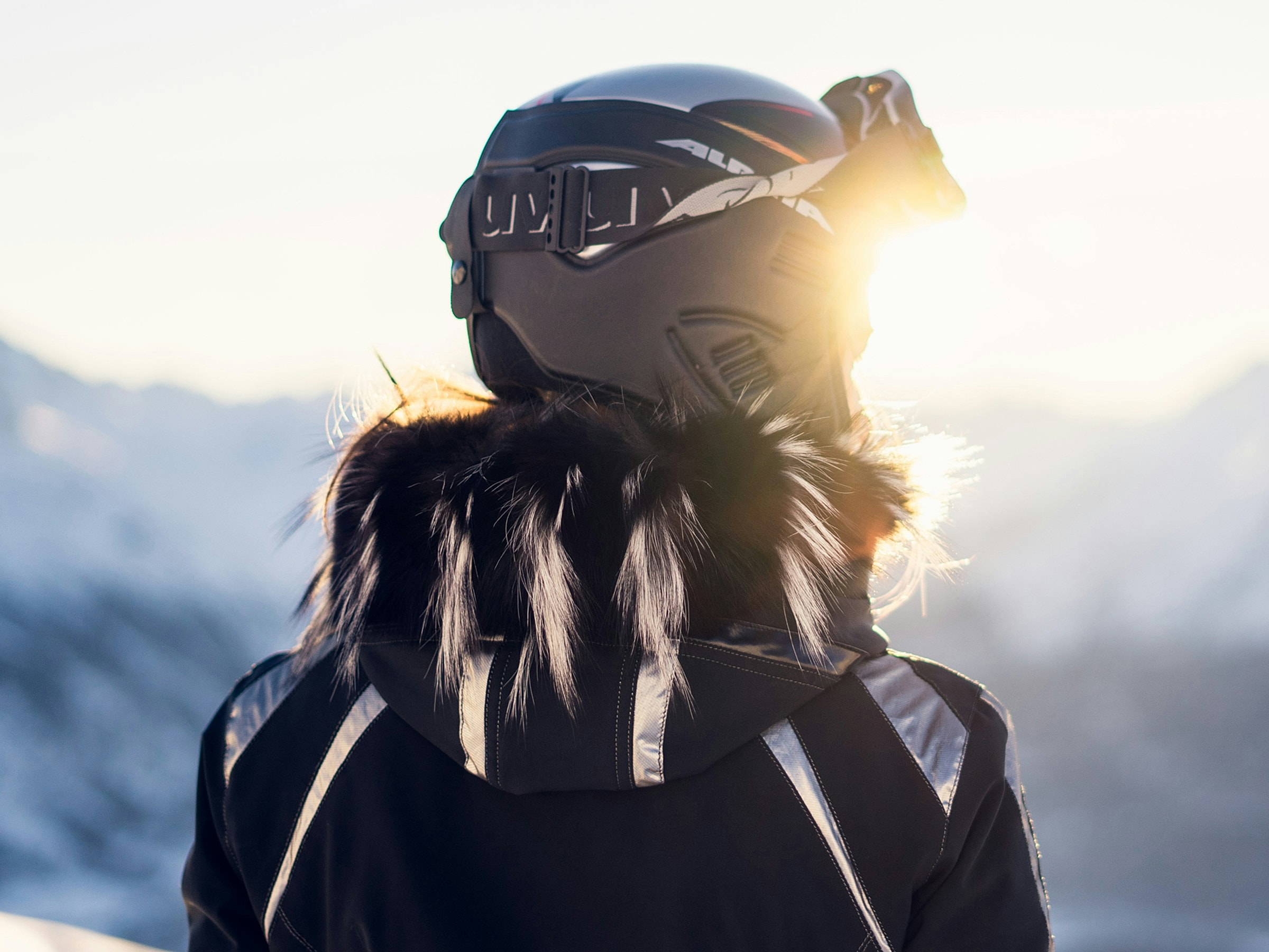 Person in ski gear overlooking snowy mountains.